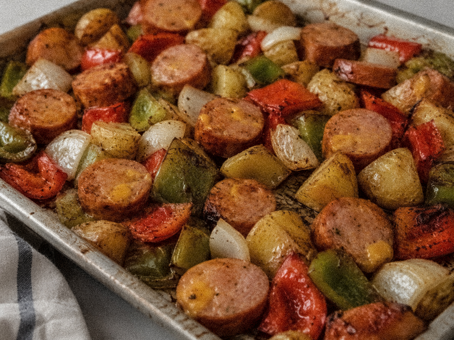 Smoked sausage sheet pan dinner with roasted potatoes, bell peppers, and onions.