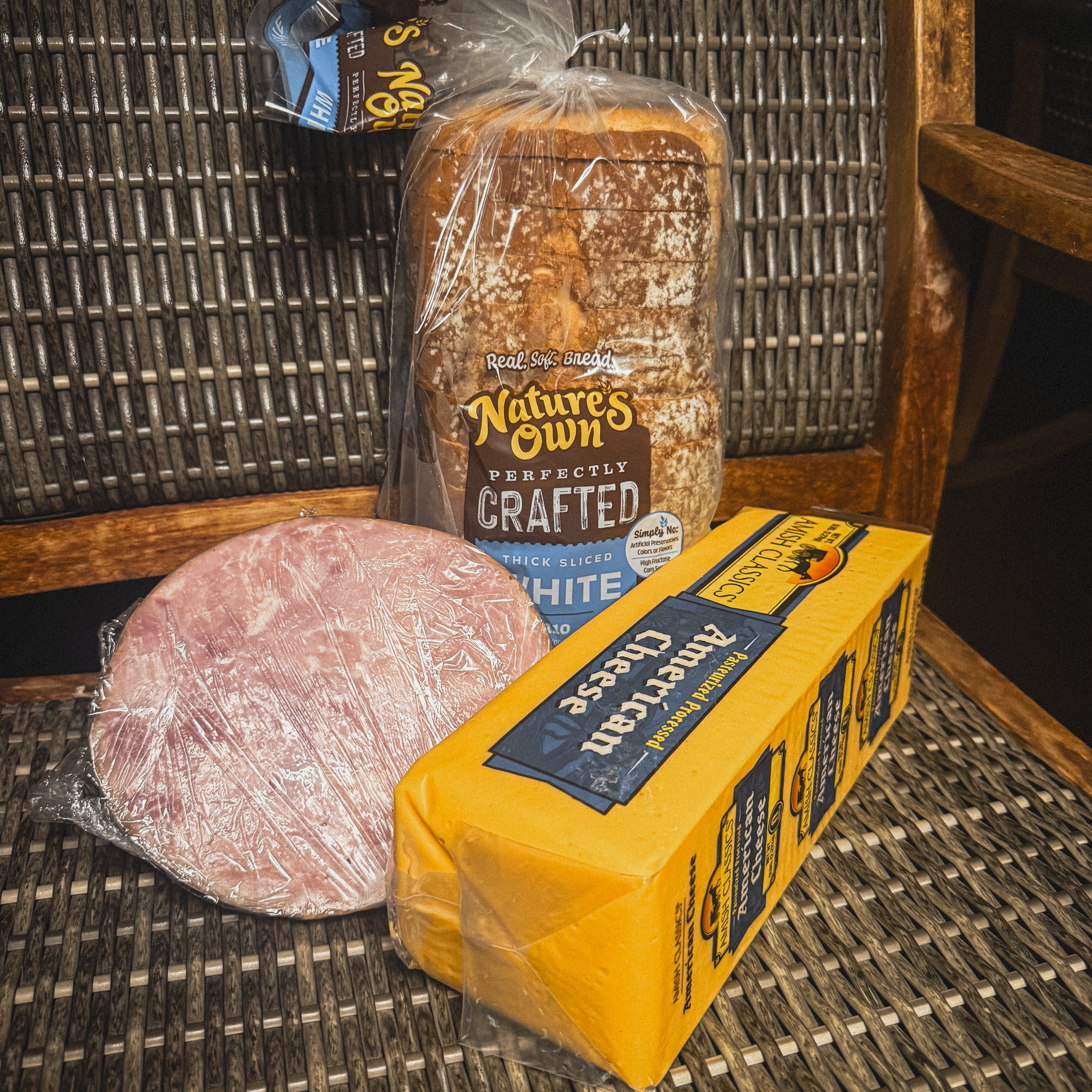 Sliced deli ham, a block of American cheese and a loaf of thick-sliced white bread